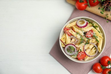 Photo of Bowl of delicious pasta with tomatoes, onion and cheese on white wooden table, flat lay. Space for text
