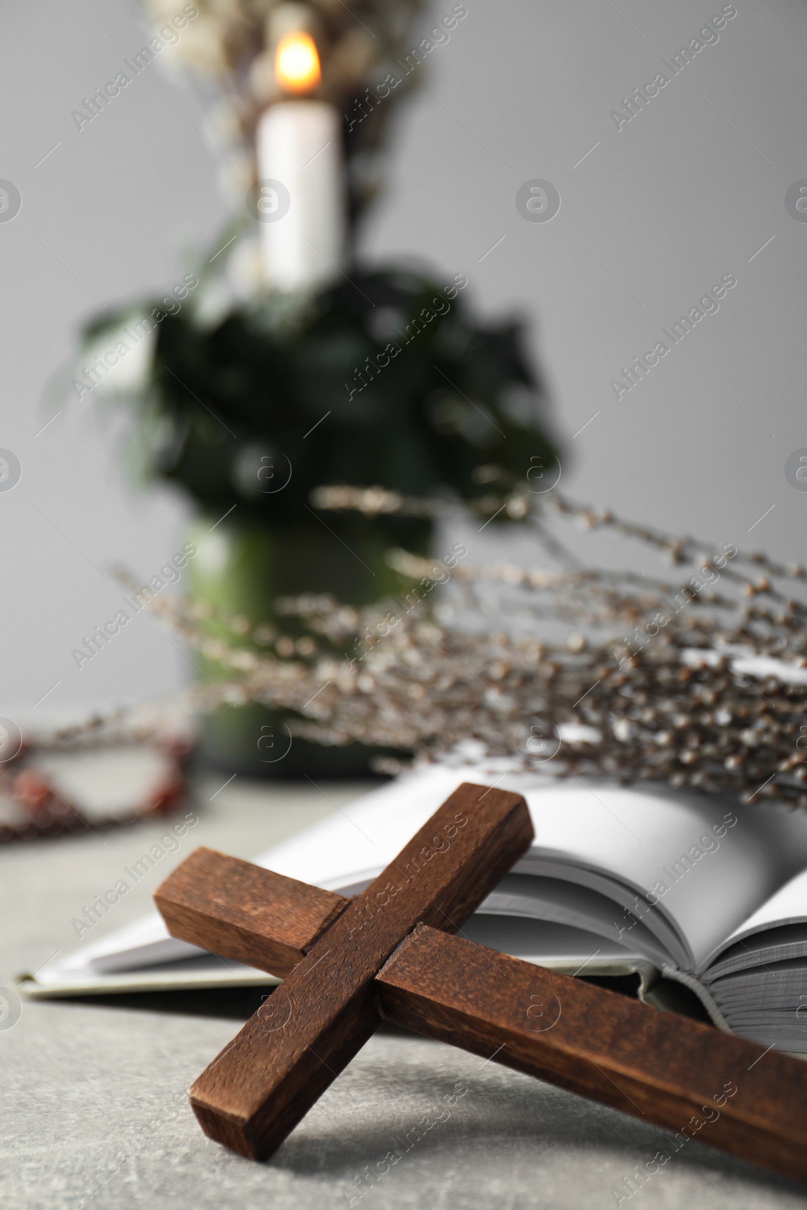 Photo of Bible and wooden cross on grey table, closeup