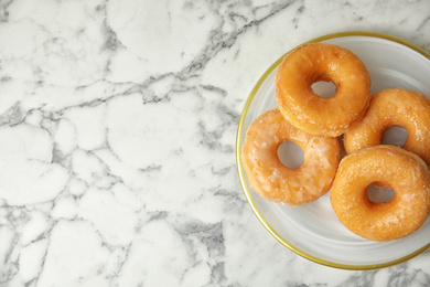 Photo of Delicious donuts on marble table, top view. Space for text