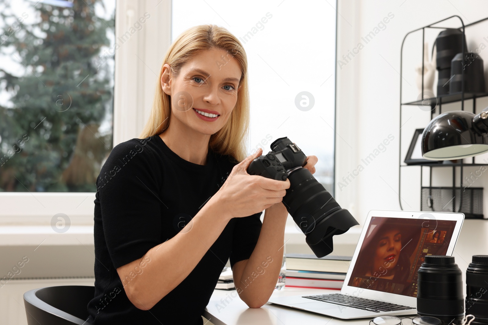 Photo of Professional photographer with digital camera at table in office