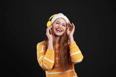 Photo of Young woman listening to music with headphones on black background