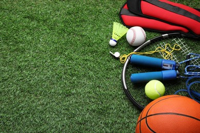 Photo of Set of different colorful sports equipment on green grass, above view. Space for text