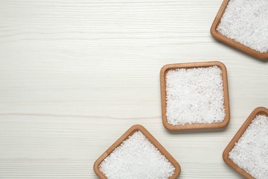 Photo of Plates with natural sea salt on white wooden table, flat lay. Space for text