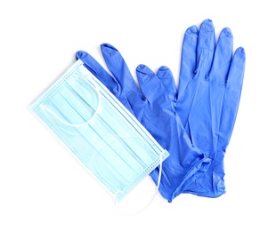 Medical gloves and protective face mask on white background, top view