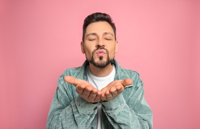 Photo of Handsome man blowing kiss on pink background