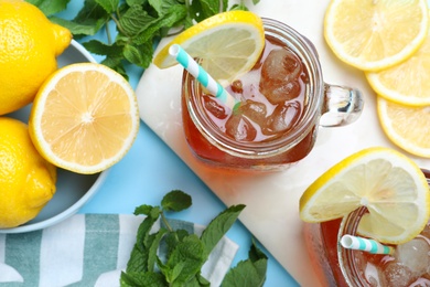 Photo of Delicious iced tea with lemon and mint on light blue background, flat lay