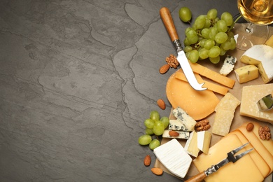 Flat lay composition with different sorts of cheese and knives on black table. Space for text