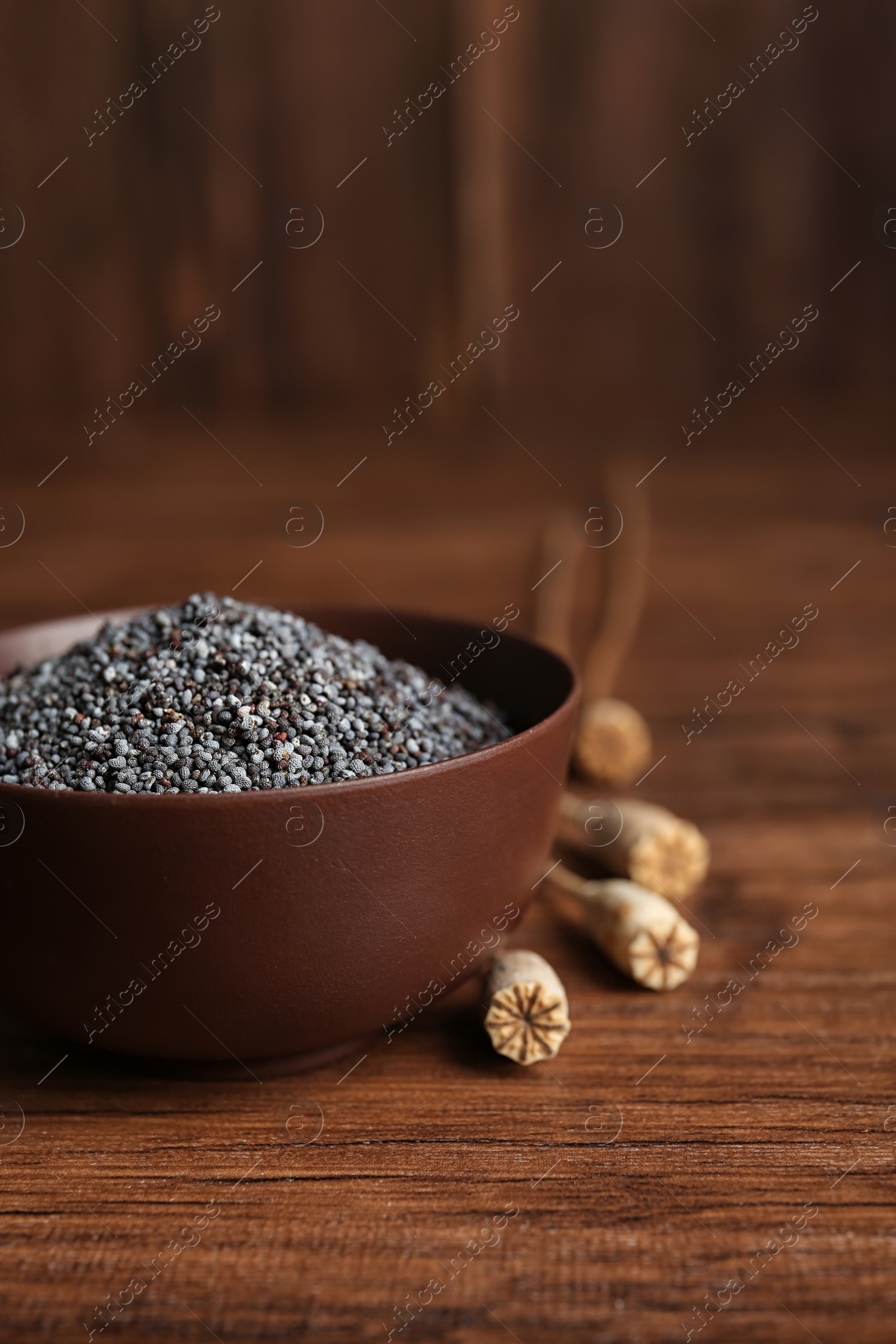 Photo of Bowl with poppy seeds on wooden table