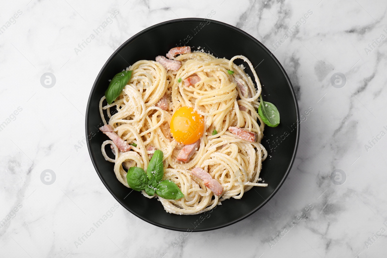 Photo of Delicious pasta Carbonara with egg yolk on white marble table, top view