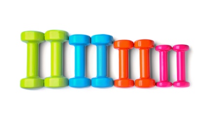 Many colorful dumbbells on white background, top view. Fitness equipment