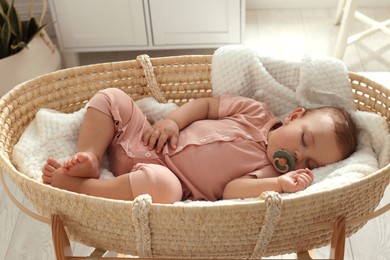 Photo of Cute little baby with pacifier sleeping in wicker crib at home