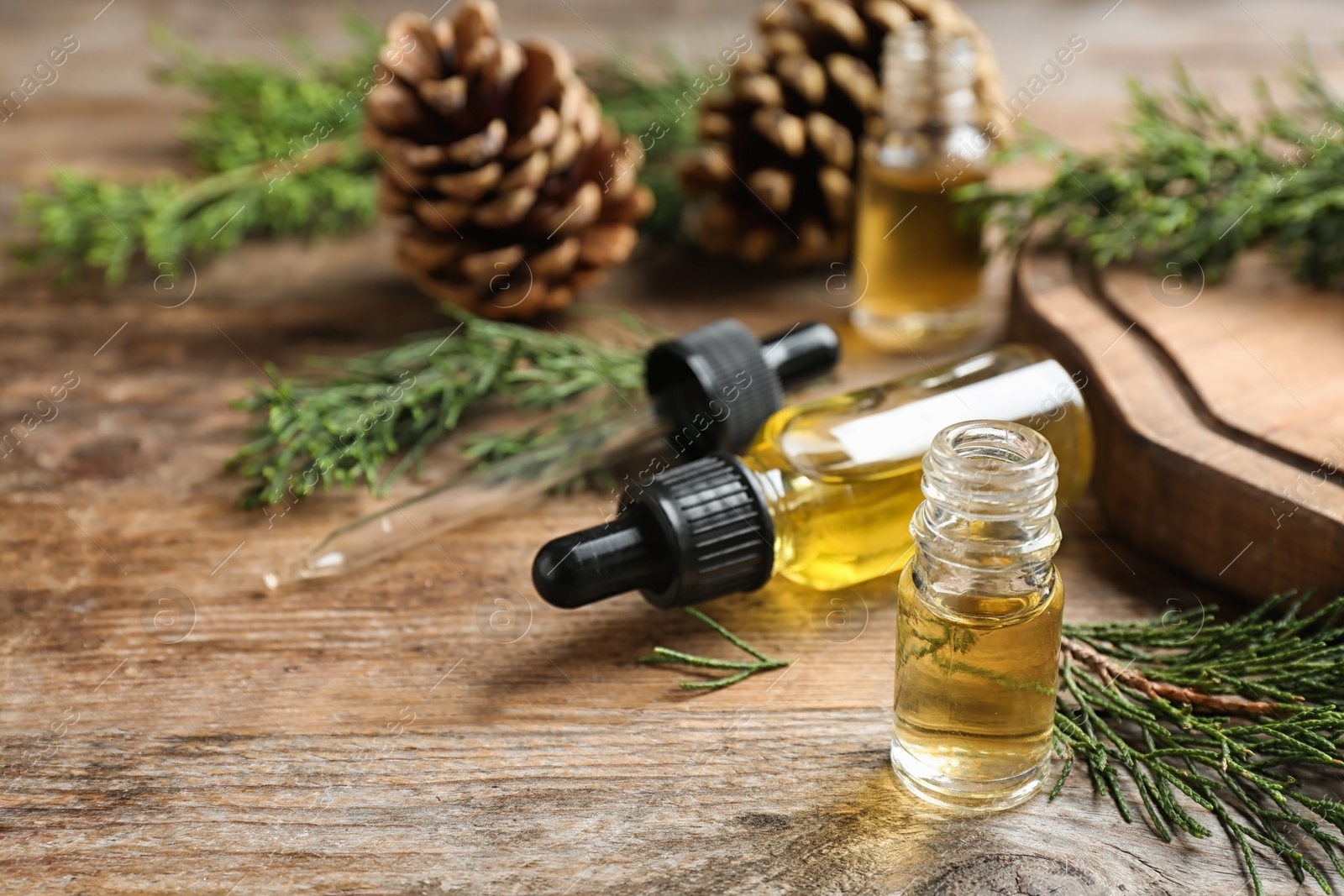 Photo of Composition with bottles of conifer essential oil on wooden table. Space for text