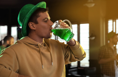 Photo of Man drinking green beer in pub. St. Patrick's Day celebration