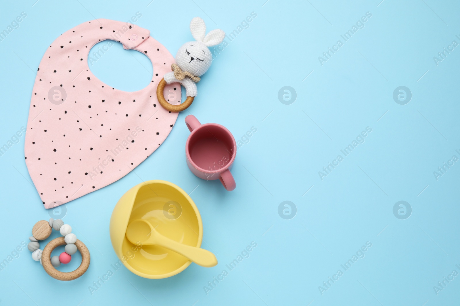 Photo of Flat lay composition with baby feeding accessories and bib on light blue background, space for text