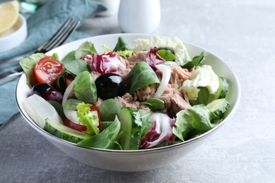 Photo of Bowl of delicious salad with canned tuna and vegetables on light grey table