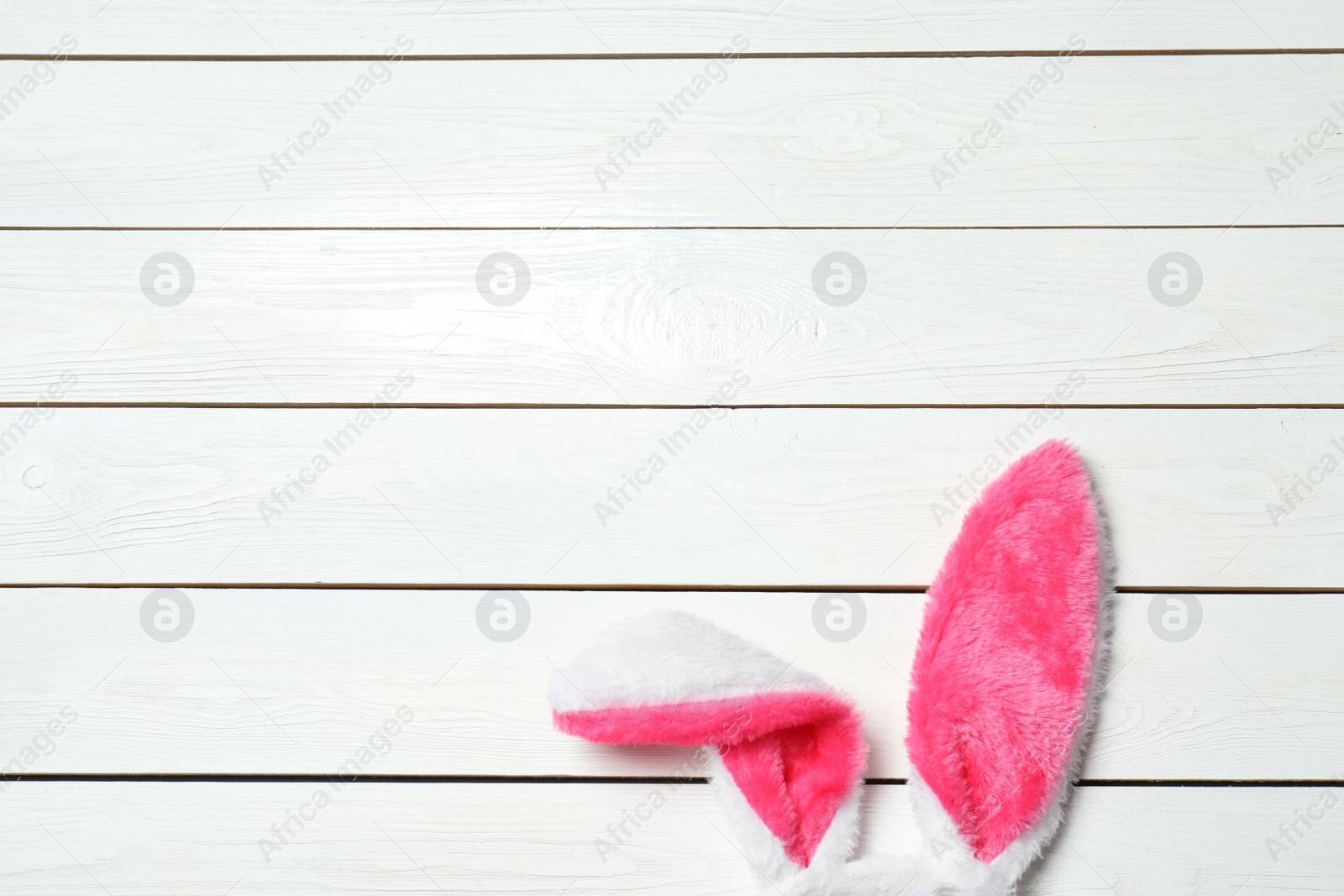 Photo of Funny Easter bunny ears on wooden background, top view with space for text