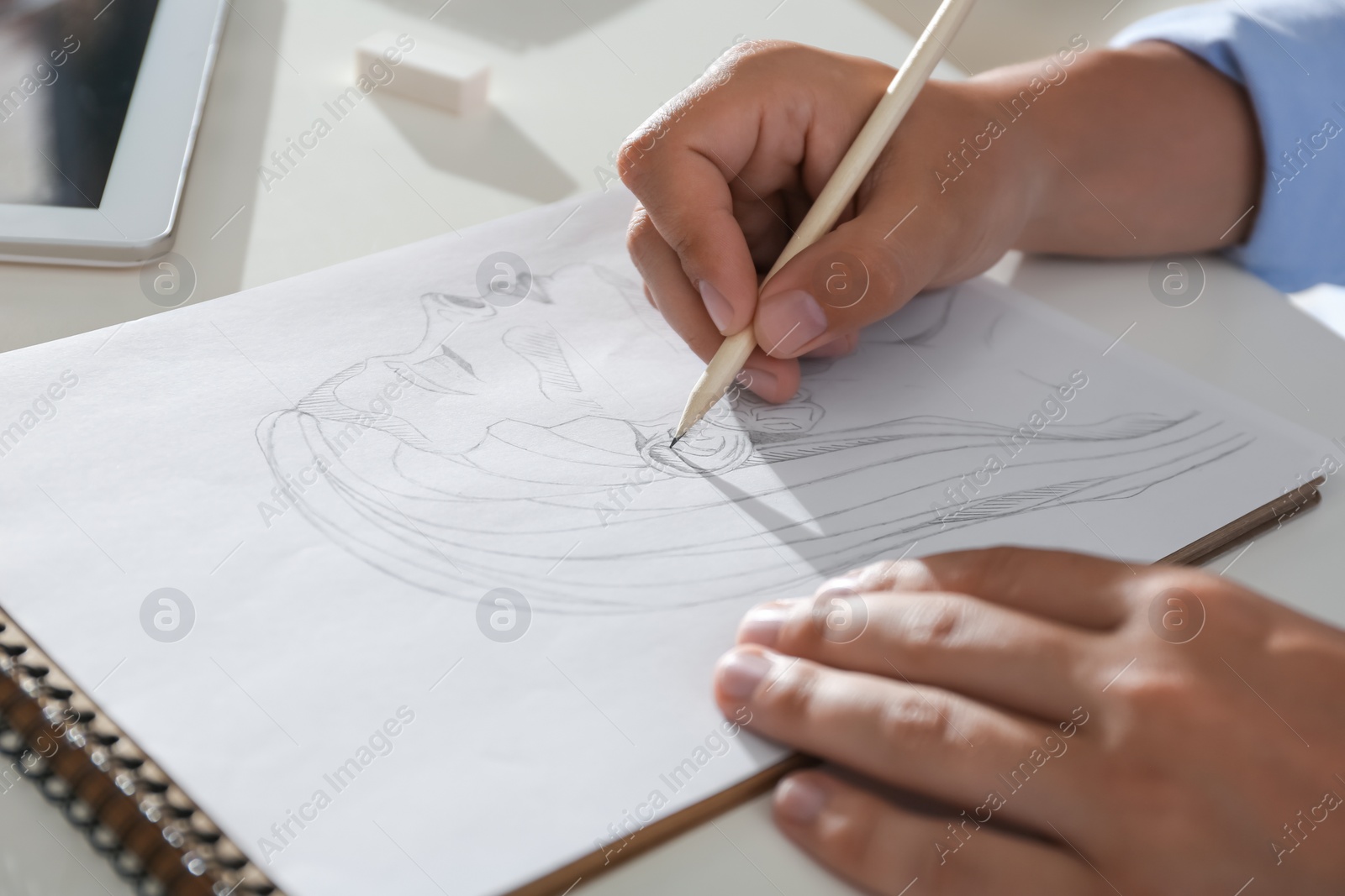 Photo of Man drawing portrait with pencil in notepad at table, closeup