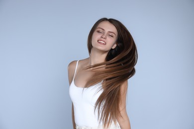 Photo of Young woman with strong healthy hair on light blue background