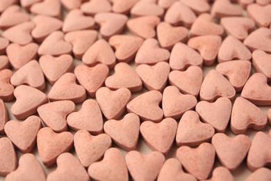 Heart shaped vitamins for pets as background, closeup