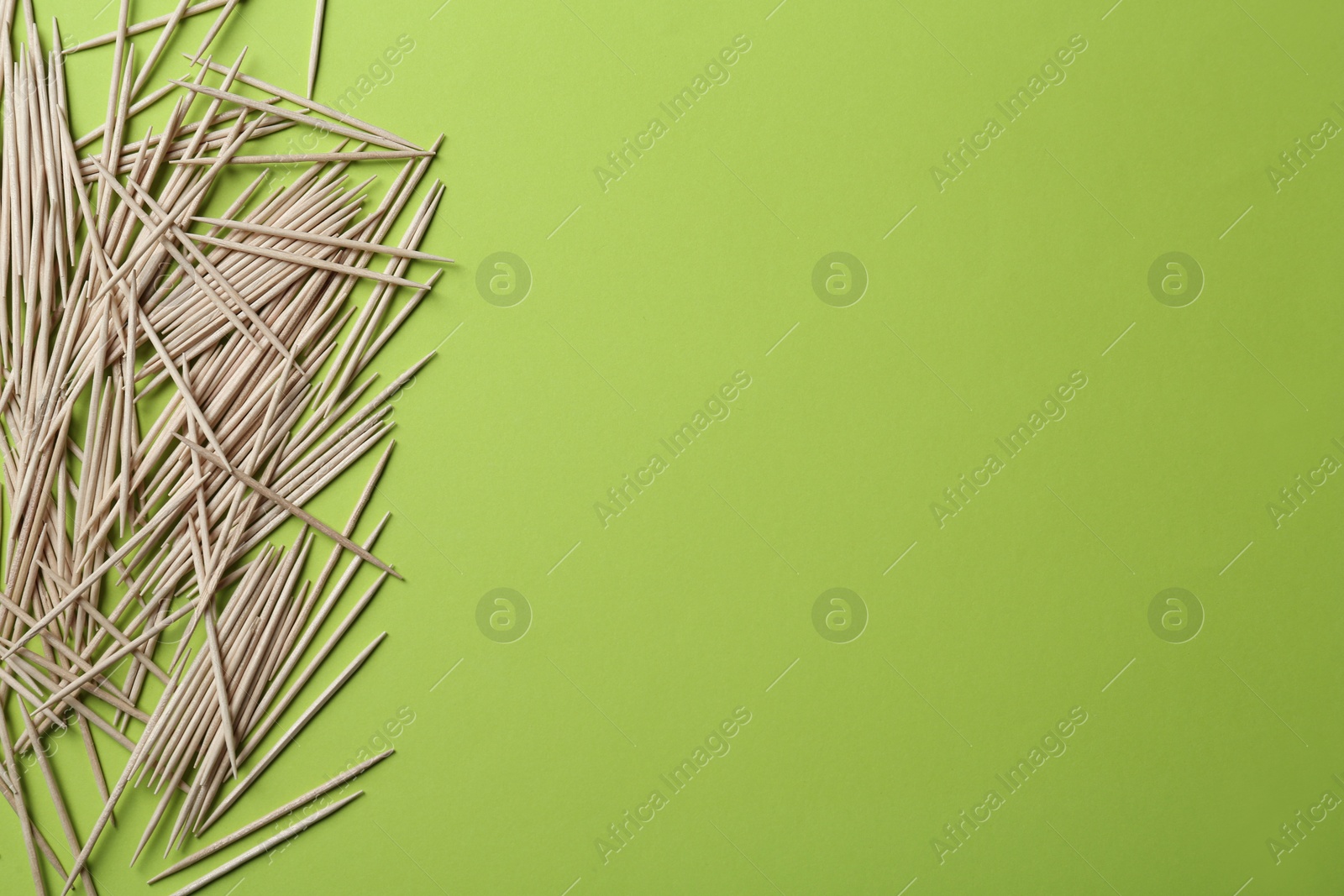 Photo of Wooden toothpicks on green background, flat lay. Space for text