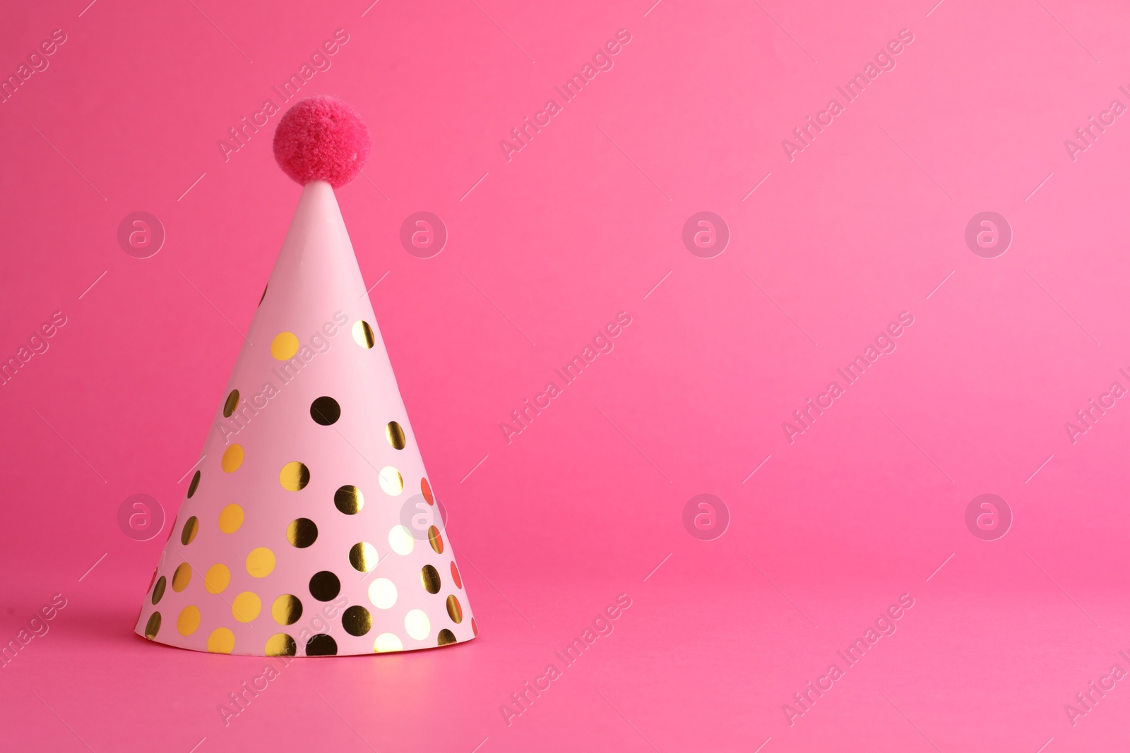 Photo of One beautiful party hat with pompom on pink background, space for text
