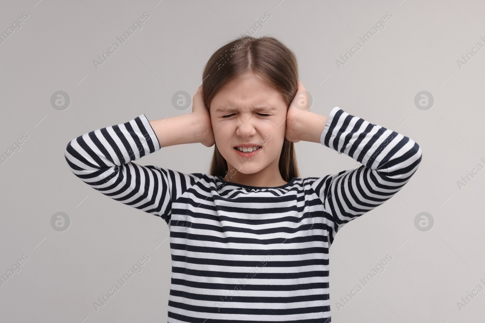 Photo of Hearing problem. Little girl suffering from ear pain on grey background