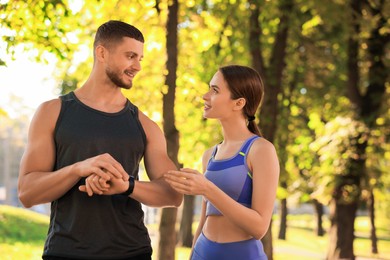 Photo of Attractive happy couple checking pulse after training in park on sunny day