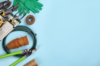 Flat lay composition with gardening tools on light blue background, space for text