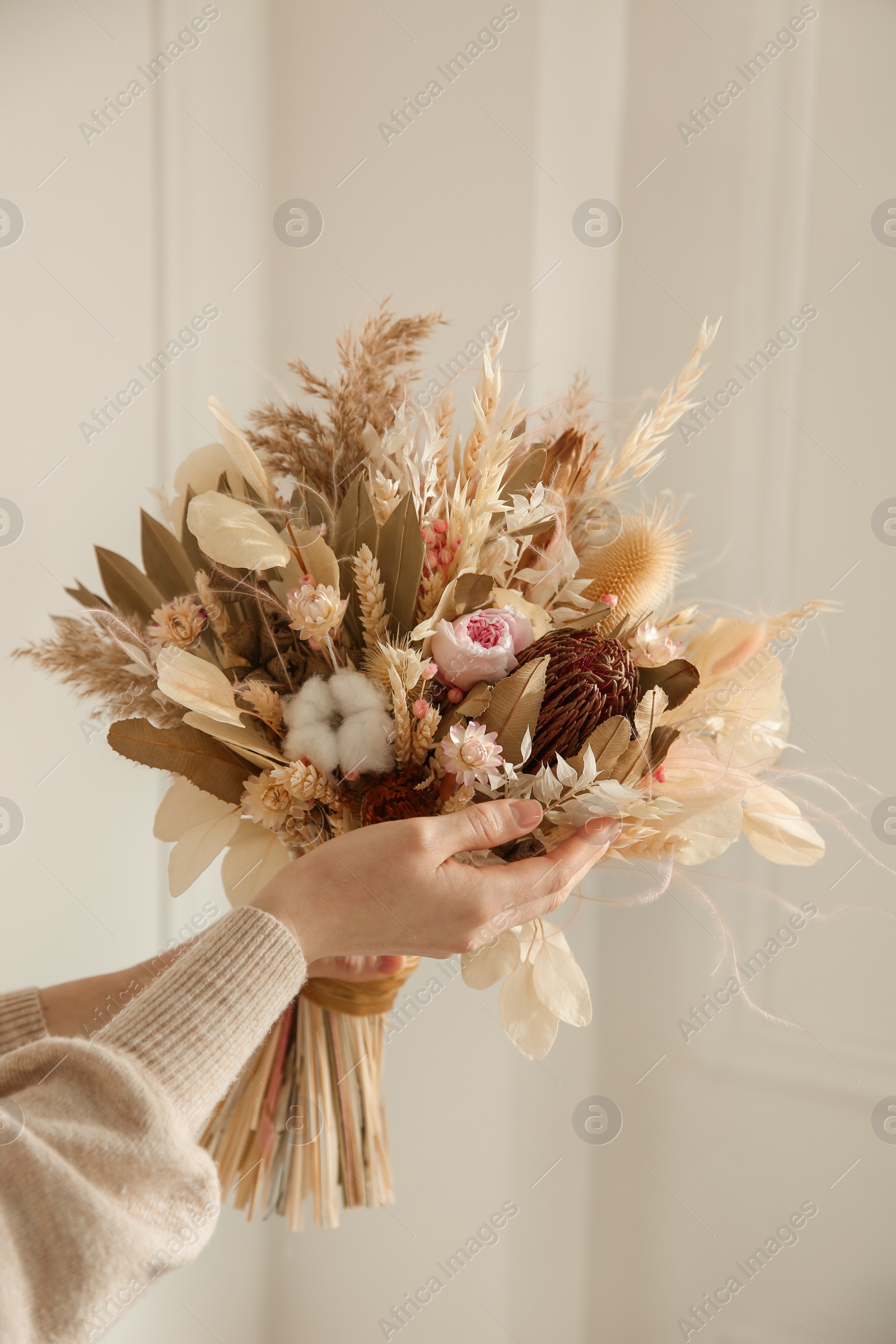 Photo of Woman holding beautiful dried flower bouquet at home, closeup