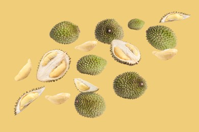 Image of Fresh ripe durians falling on pale yellow background