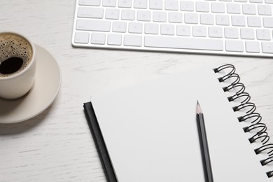 Photo of Open blank notebook, pencil, coffee and keyboard on white wooden table