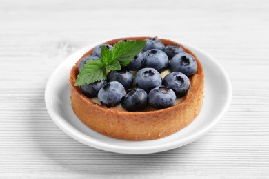 Tartlet with fresh blueberries on white wooden table, closeup. Delicious dessert