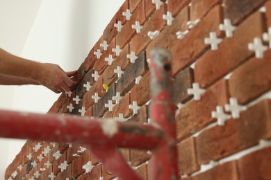Photo of Professional builder gluing decorative brick on wall, closeup. Tiles installation process