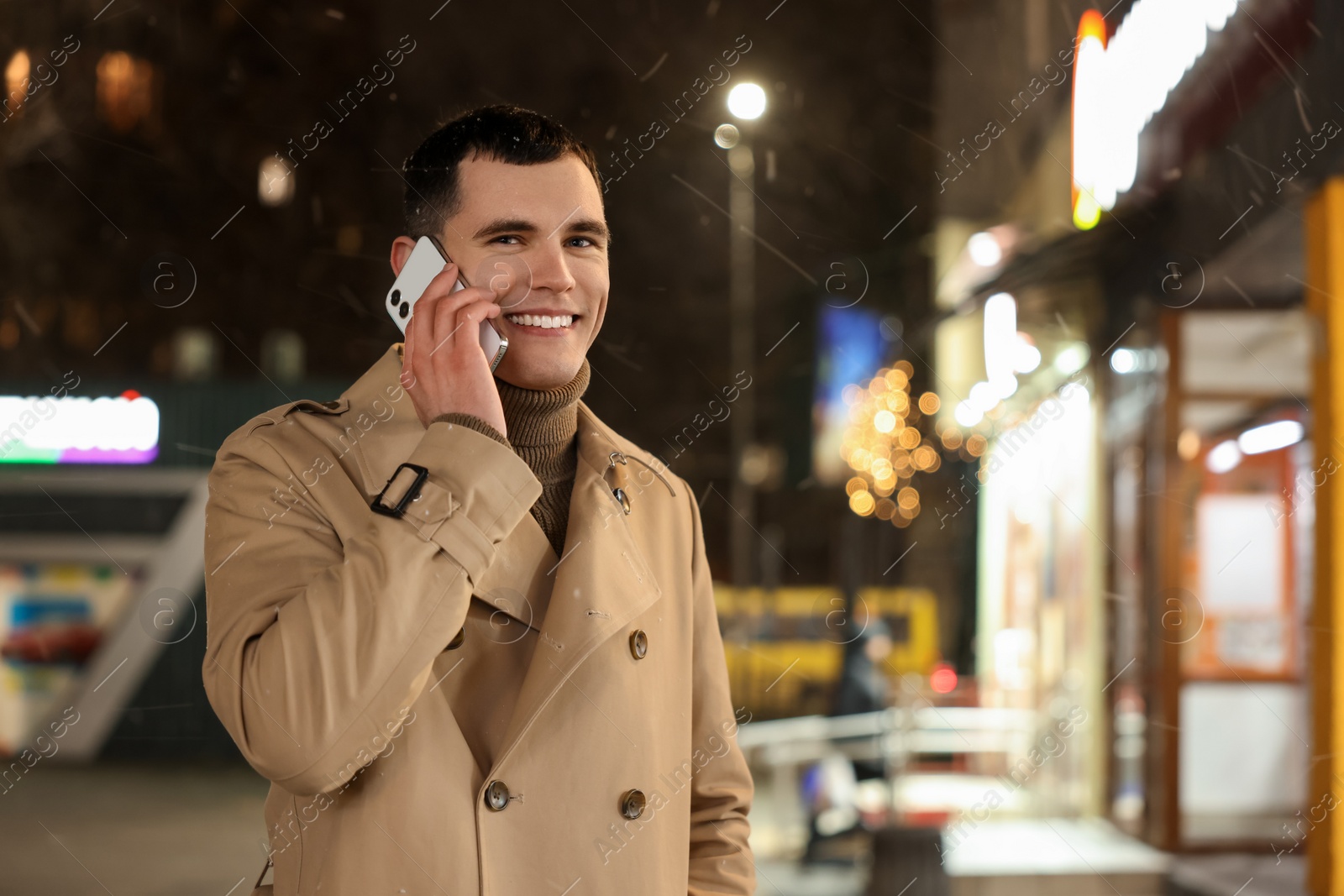 Photo of Man talking by smartphone on night city street, space for text