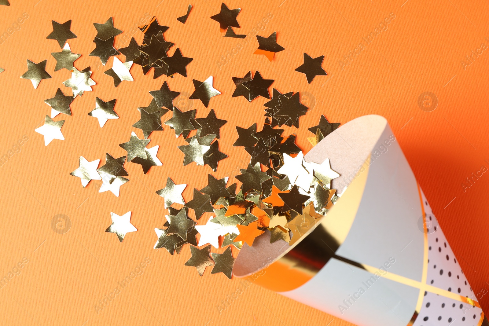 Photo of Party hat and confetti on orange background, flat lay