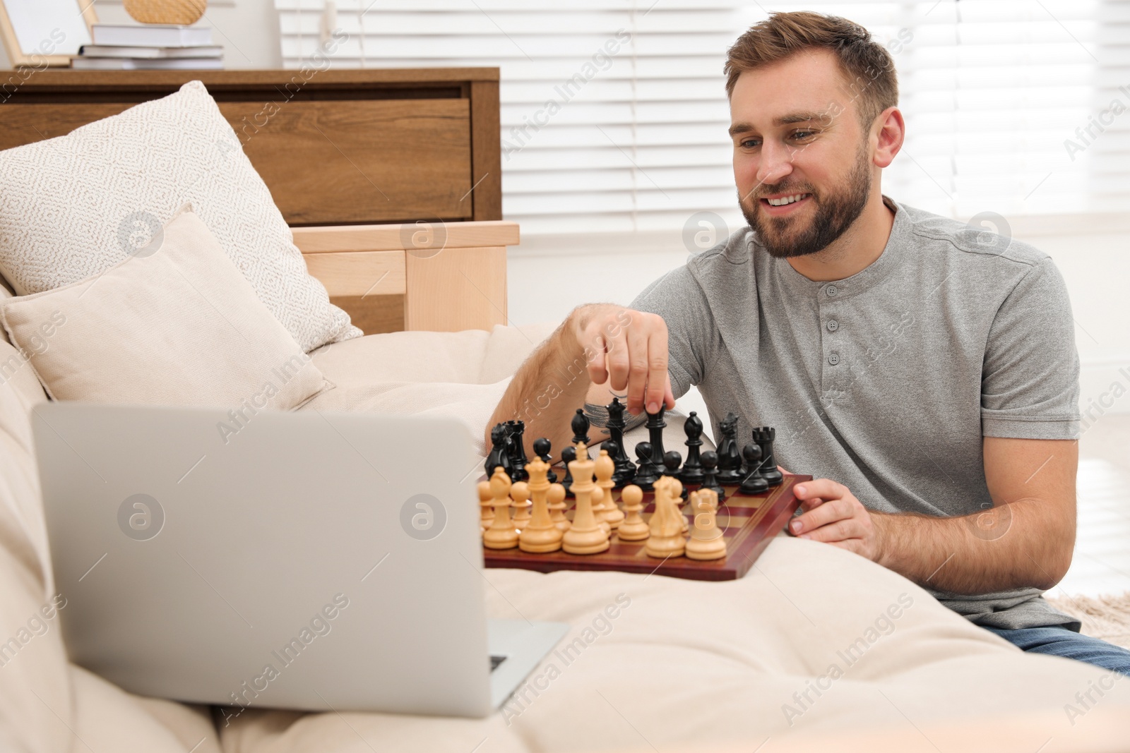 Photo of Young man playing chess with partner through online video chat at home