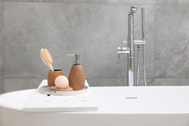 Photo of Different personal care products and accessories on bath tub in bathroom, space for text