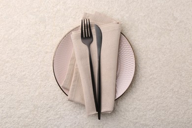 Stylish setting with elegant cutlery on beige textured table, top view