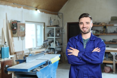 Photo of Young working man in uniform at carpentry shop, space for text