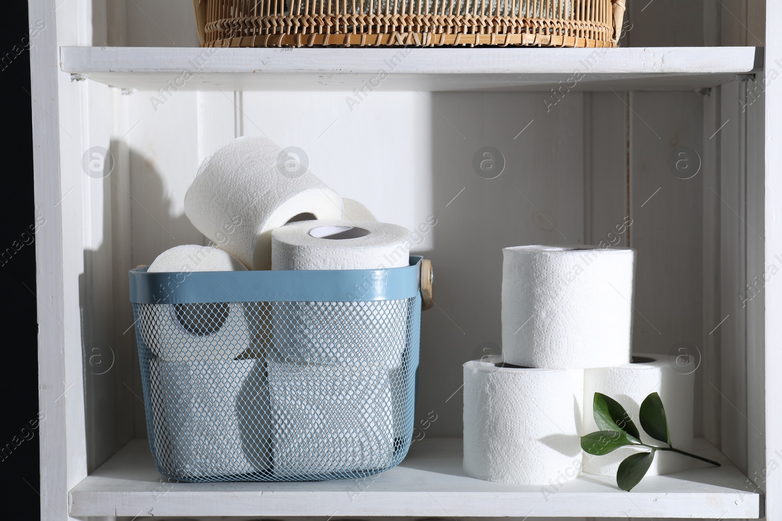 Photo of Toilet paper rolls and green leaves on white shelf