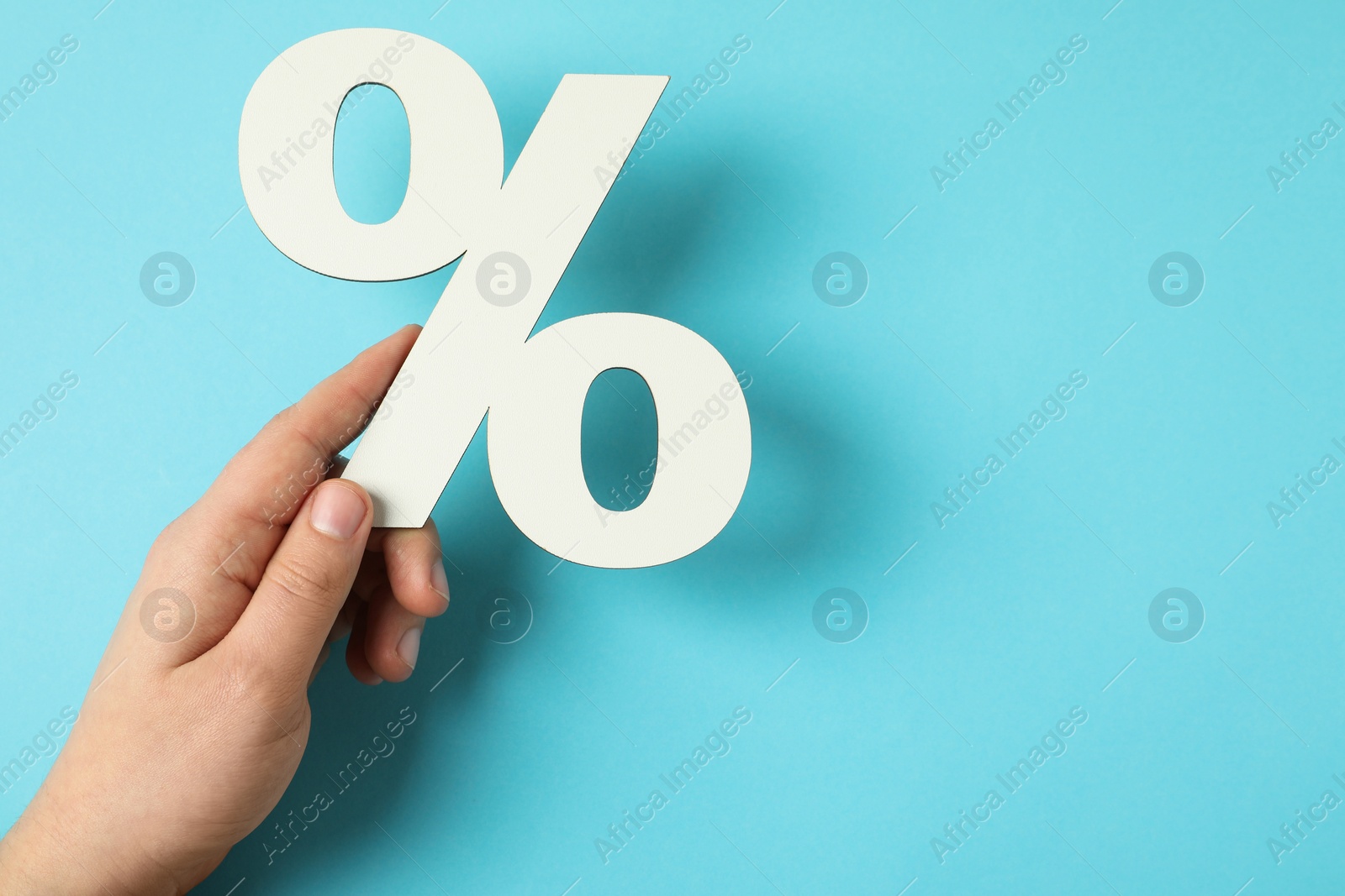 Photo of Man holding percent sign on light blue background, top view. Space for text