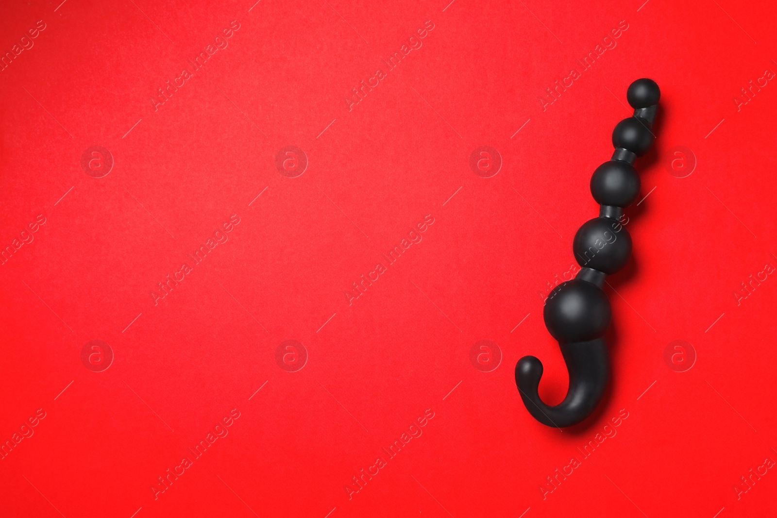 Photo of Black anal ball beads on red background, top view with space for text. Sex toy