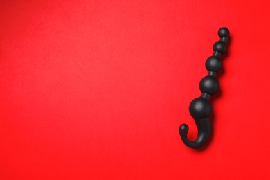 Photo of Black anal ball beads on red background, top view with space for text. Sex toy