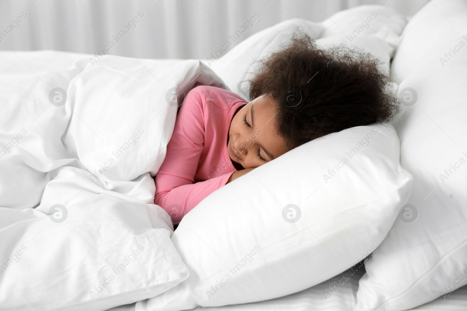 Photo of Cute little African-American girl sleeping in bed