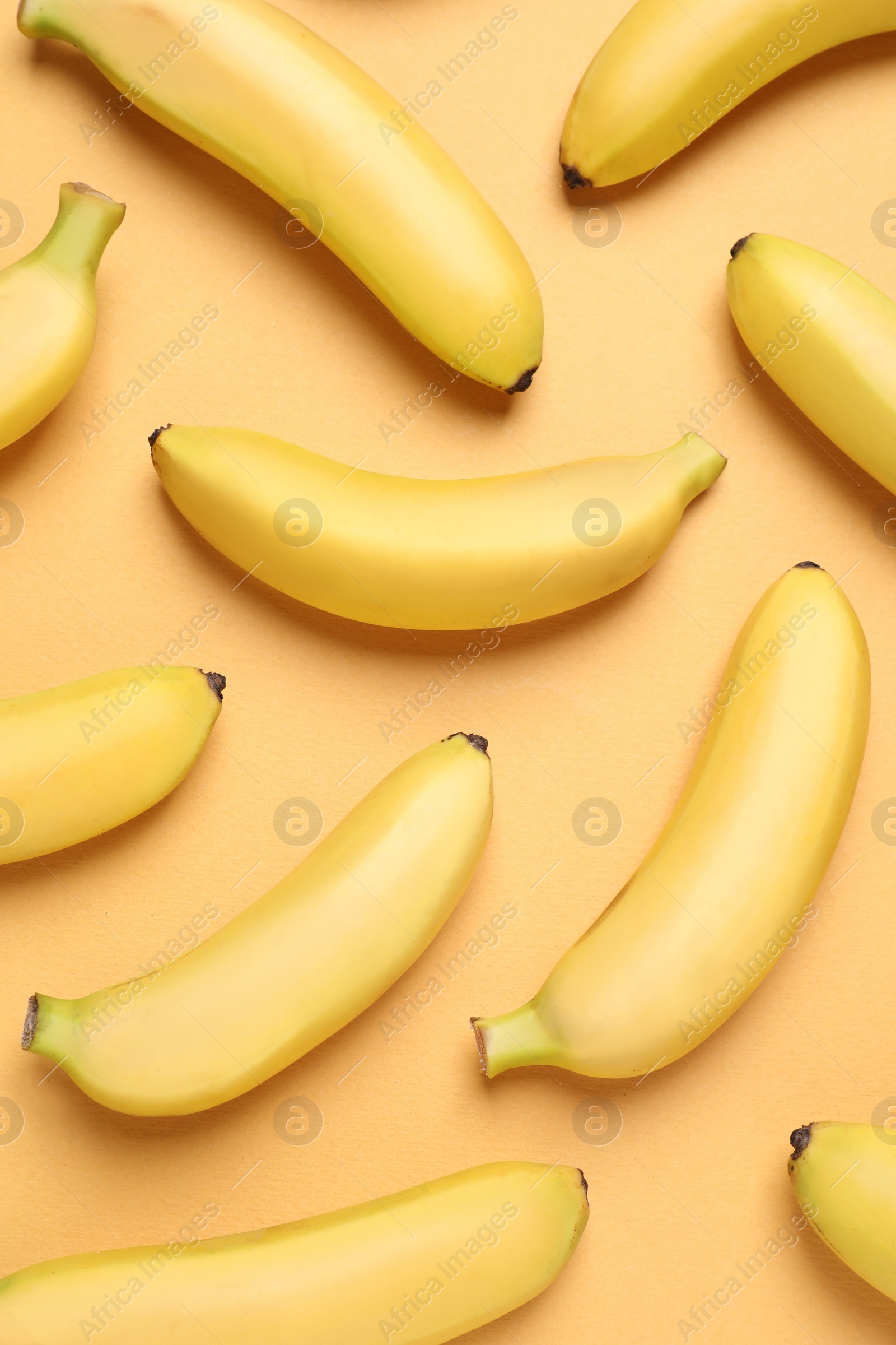 Photo of Sweet ripe baby bananas on light orange background, flat lay