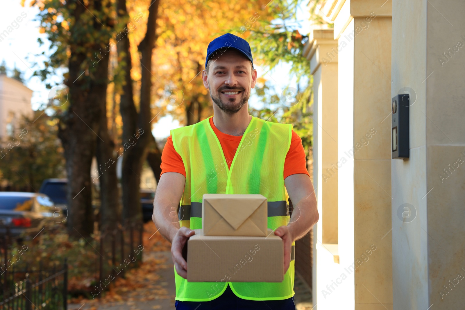 Photo of Courier in uniform with two parcels outdoors