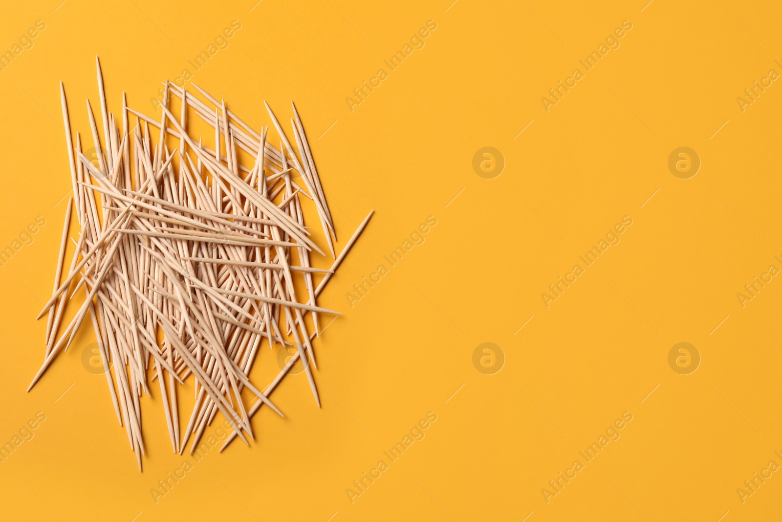 Photo of Wooden toothpicks on orange background, flat lay. Space for text