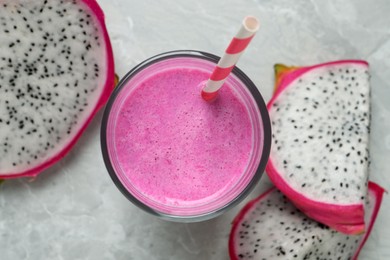 Photo of Glass of tasty pitahaya smoothie and fresh dragon fruits on light grey table, flat lay