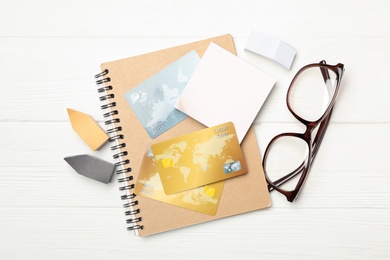Photo of Credit cards, stationery and glasses on white wooden background, flat lay