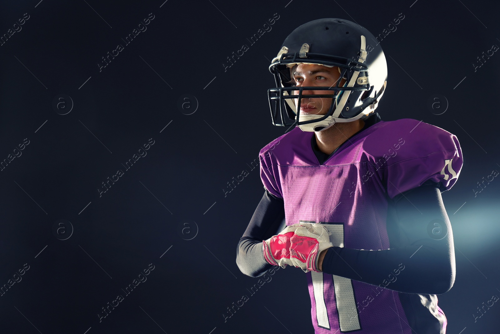 Photo of American football player in uniform on dark background